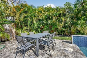 Eine möblierte Terrasse im Freien, umgeben von üppiger tropischer Vegetation.