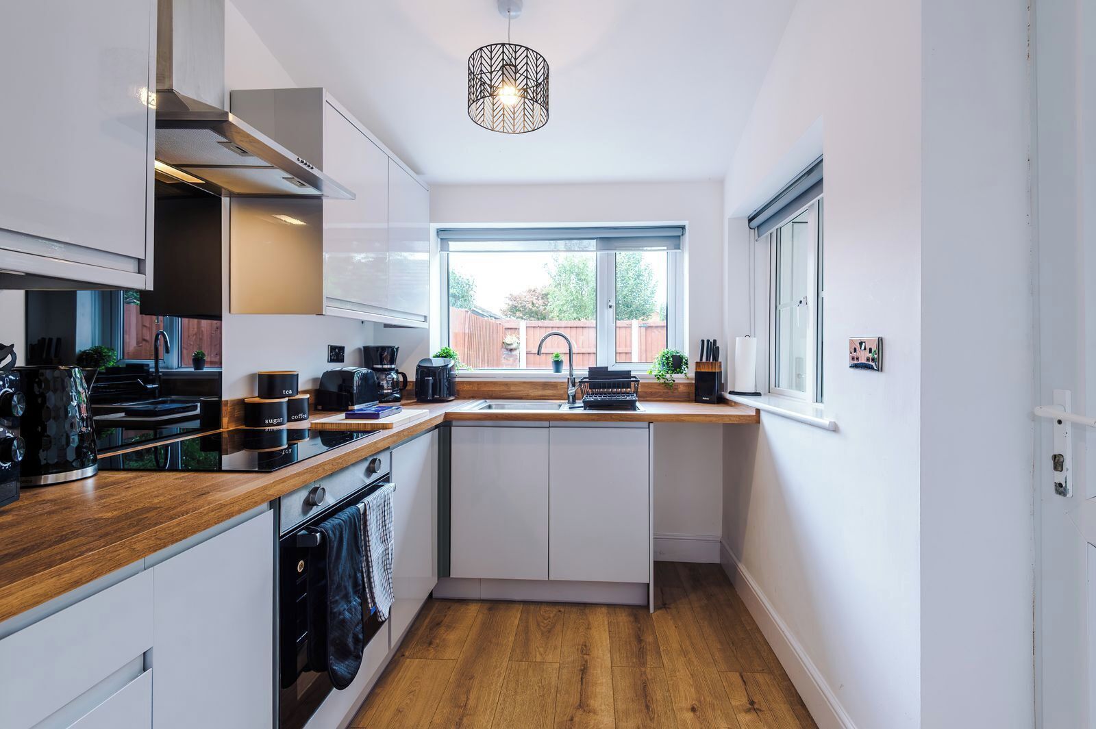 A modern kitchen with a wooden countertop, built-in appliances, and a window providing a view of the outdoors.