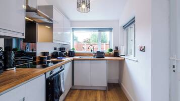 A modern kitchen with a wooden countertop, built-in appliances, and a window providing a view of the outdoors.