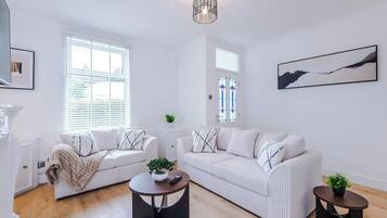 A modern living room with two white sofas, a round coffee table, and a small side table with a plant.