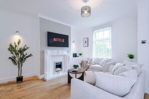 Uma sala de estar moderna com lareira, TV de tela plana e um sofá.