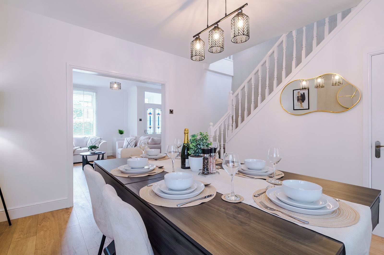 A dining area with a long table set for a meal, a staircase, and a mirror on the wall.