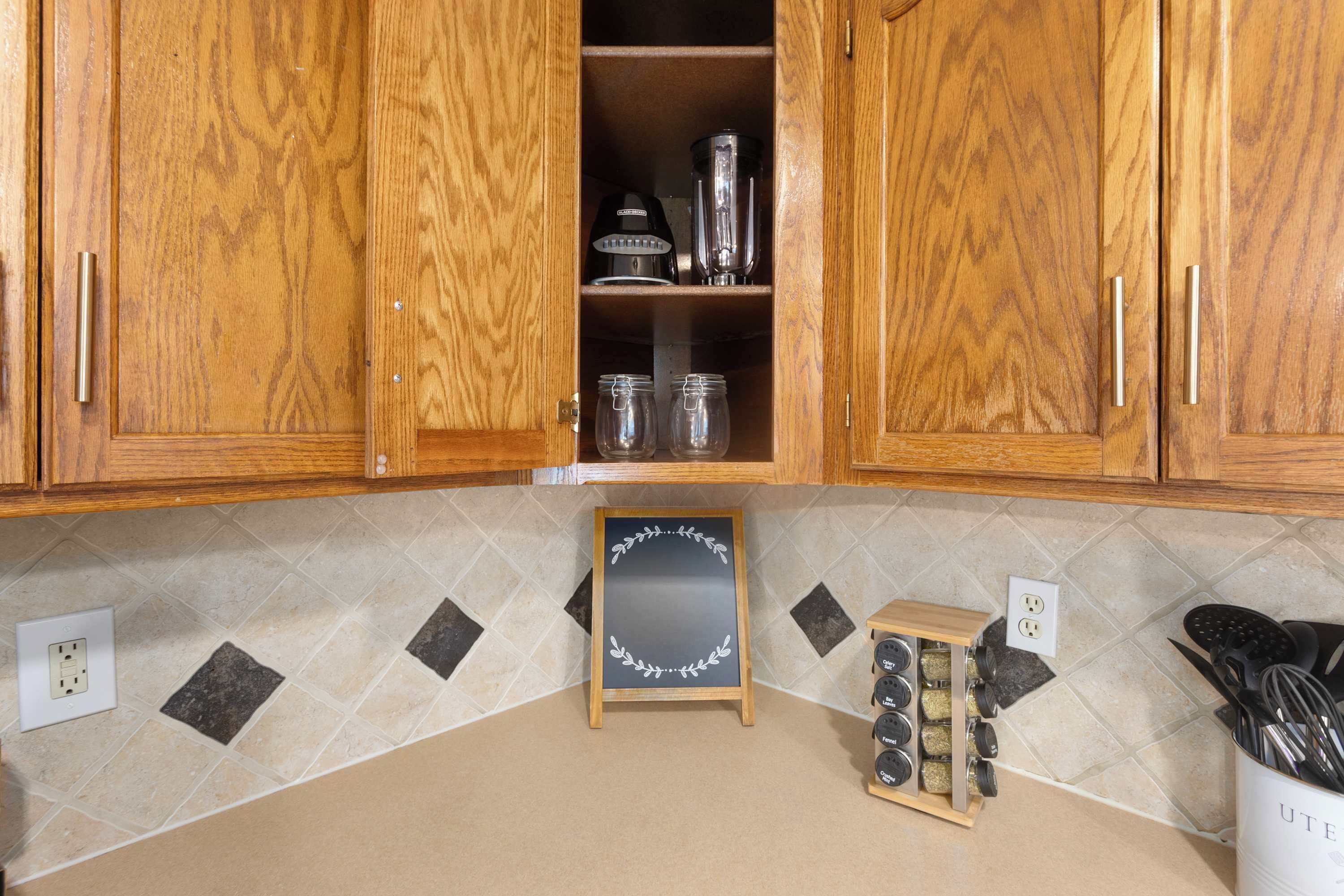 A kitchen with wooden cabinets, a chalkboard with writing, and a spice rack.
