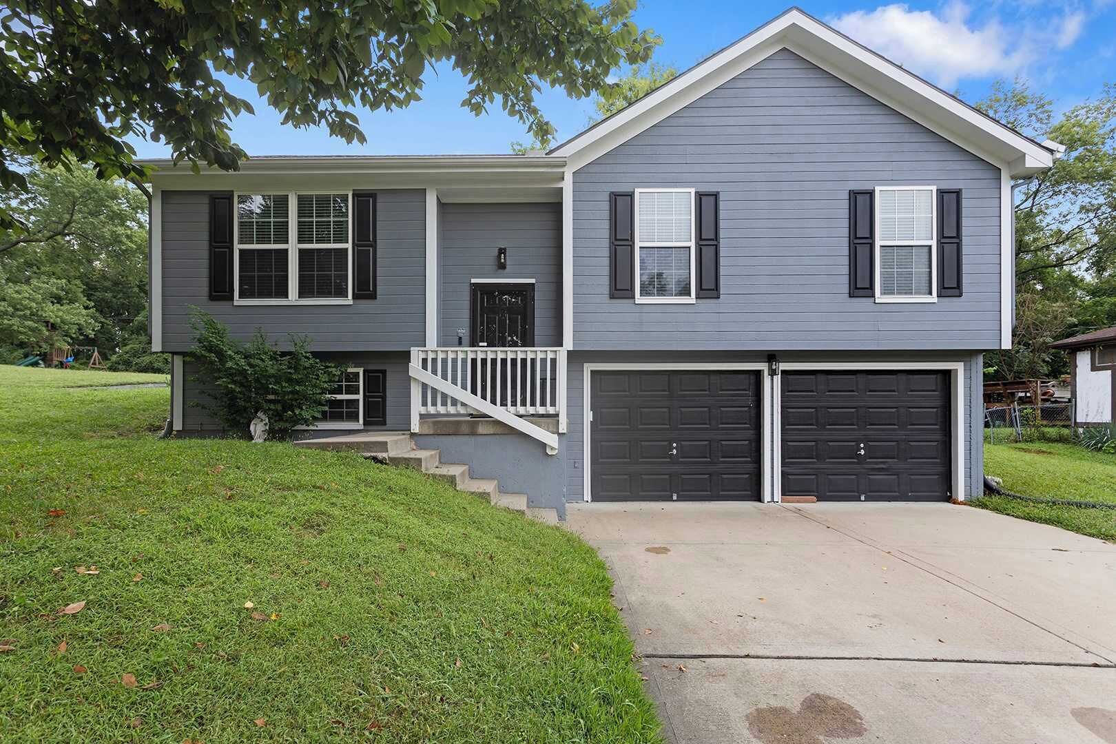 A two-story house with a front porch, a garage, and a well-maintained lawn.
