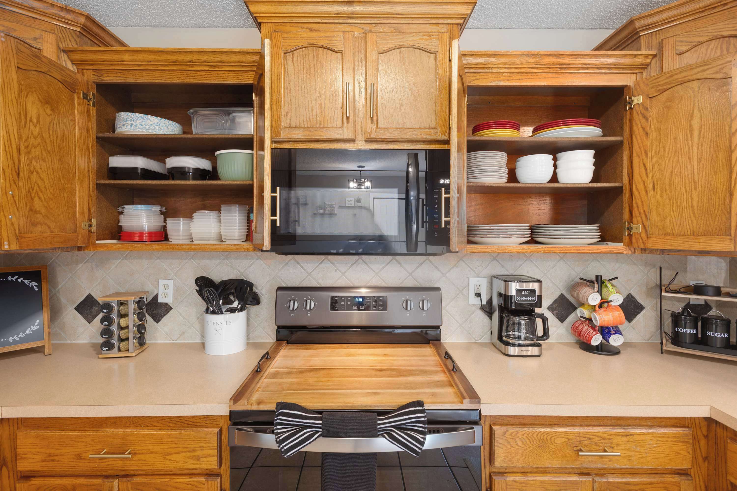 Una cocina con armarios de madera, un refrigerador de acero inoxidable, un microondas, una cafetera y diversos utensilios de cocina.