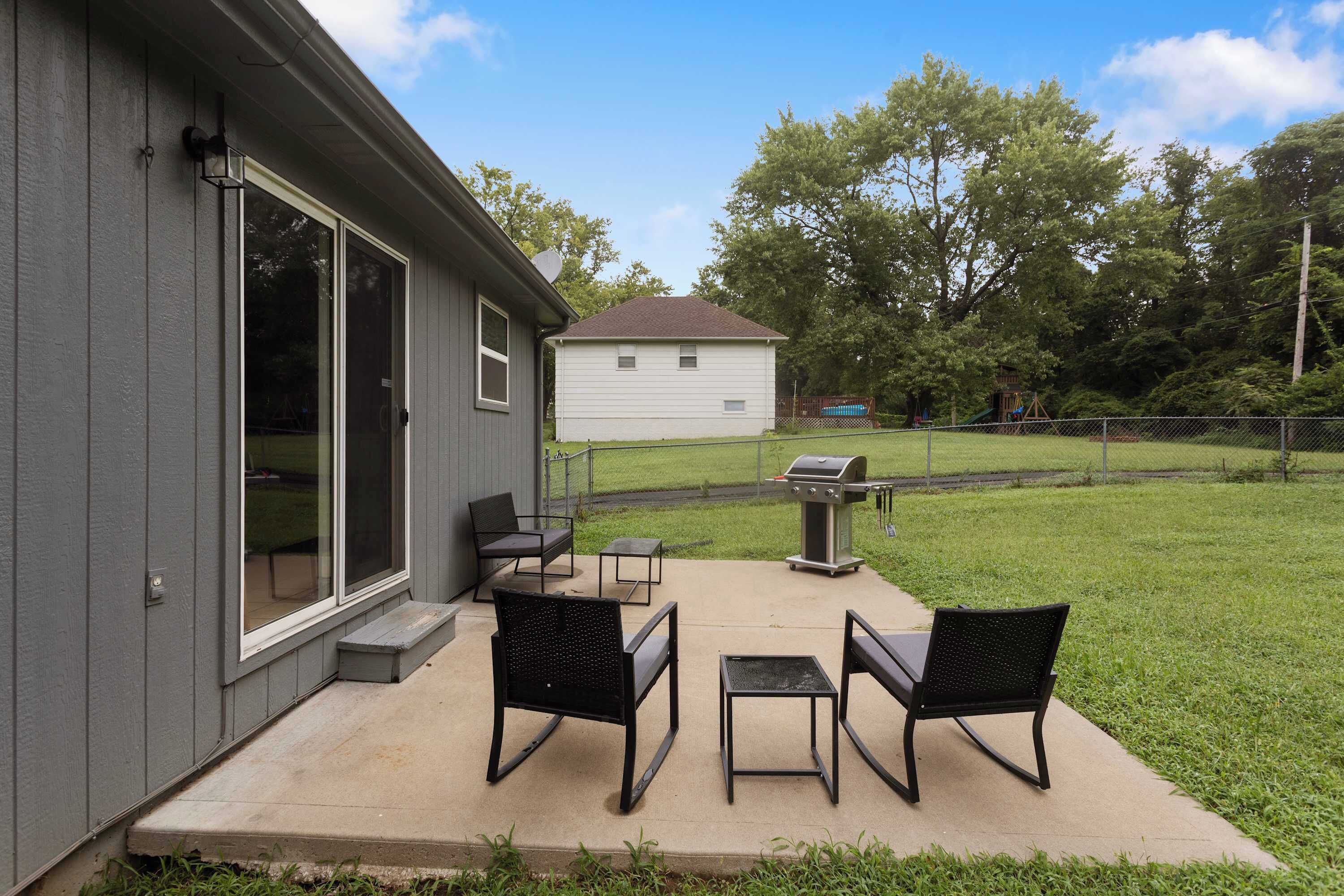 A residential property with a patio area featuring outdoor furniture, a barbecue grill, and a screened-in sliding glass door.