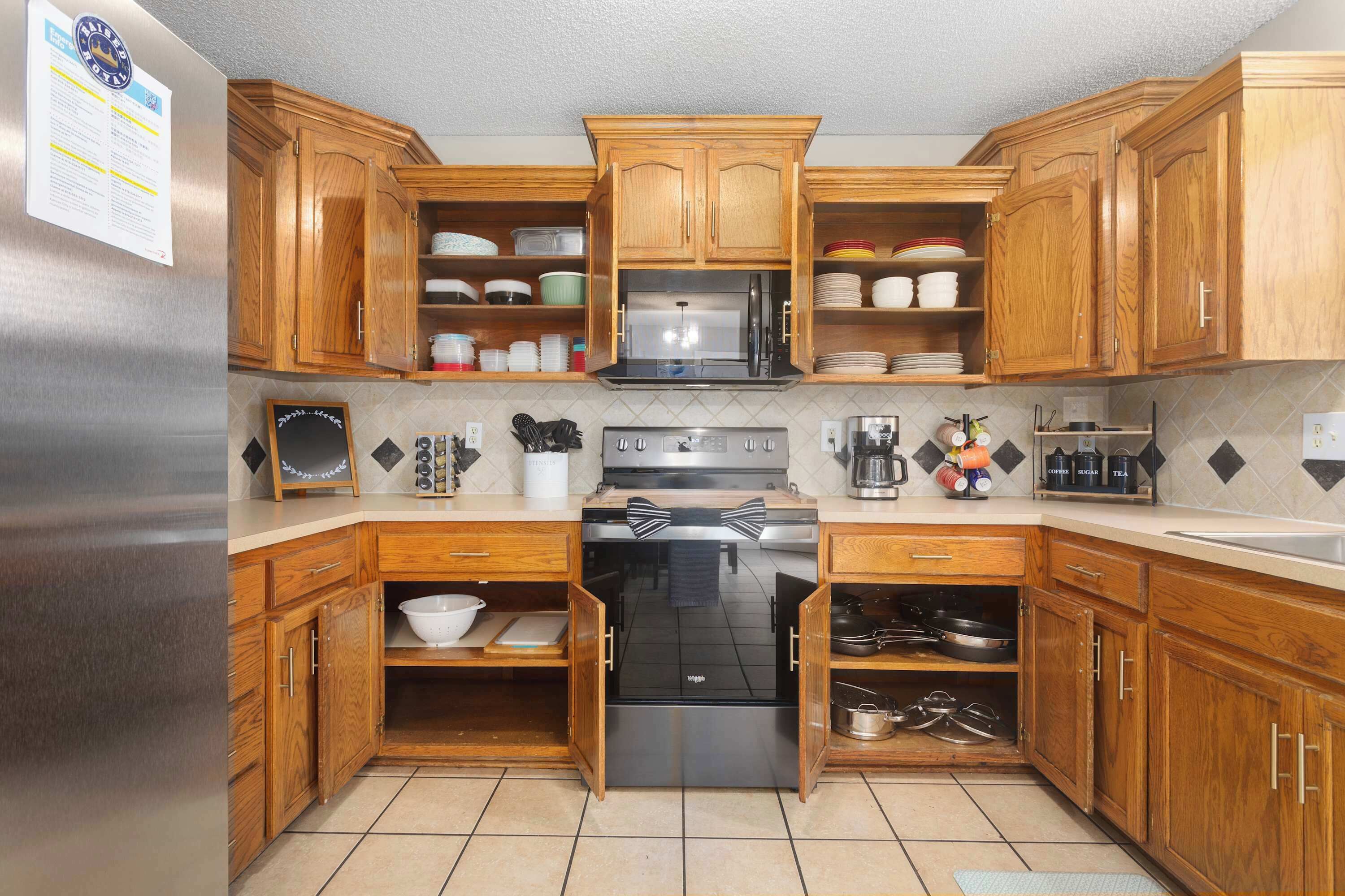 A kitchen with wooden cabinets, a stainless steel refrigerator, a microwave, and a stove.