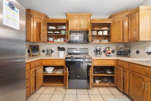 Una cocina con armarios de madera, un refrigerador de acero inoxidable, un microondas y una estufa.