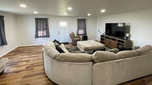 A living room with a large sofa, a television, and a wooden cabinet.