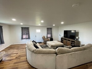 Una sala de estar con un sofá grande, un televisor y un aparador de madera.