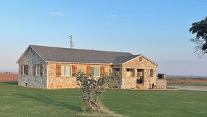 A stone house with a sloped roof, a front porch, and a small garden.
