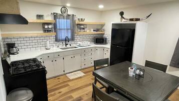 A compact kitchen with white cabinets, a black stove, a microwave, and a refrigerator.