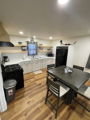 A compact kitchen with white cabinets, a black stove, a microwave, and a refrigerator.