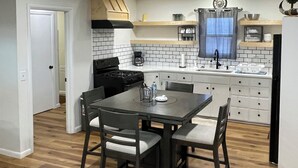A modern kitchen with white cabinets, a black countertop, and a dining area with a table and chairs.