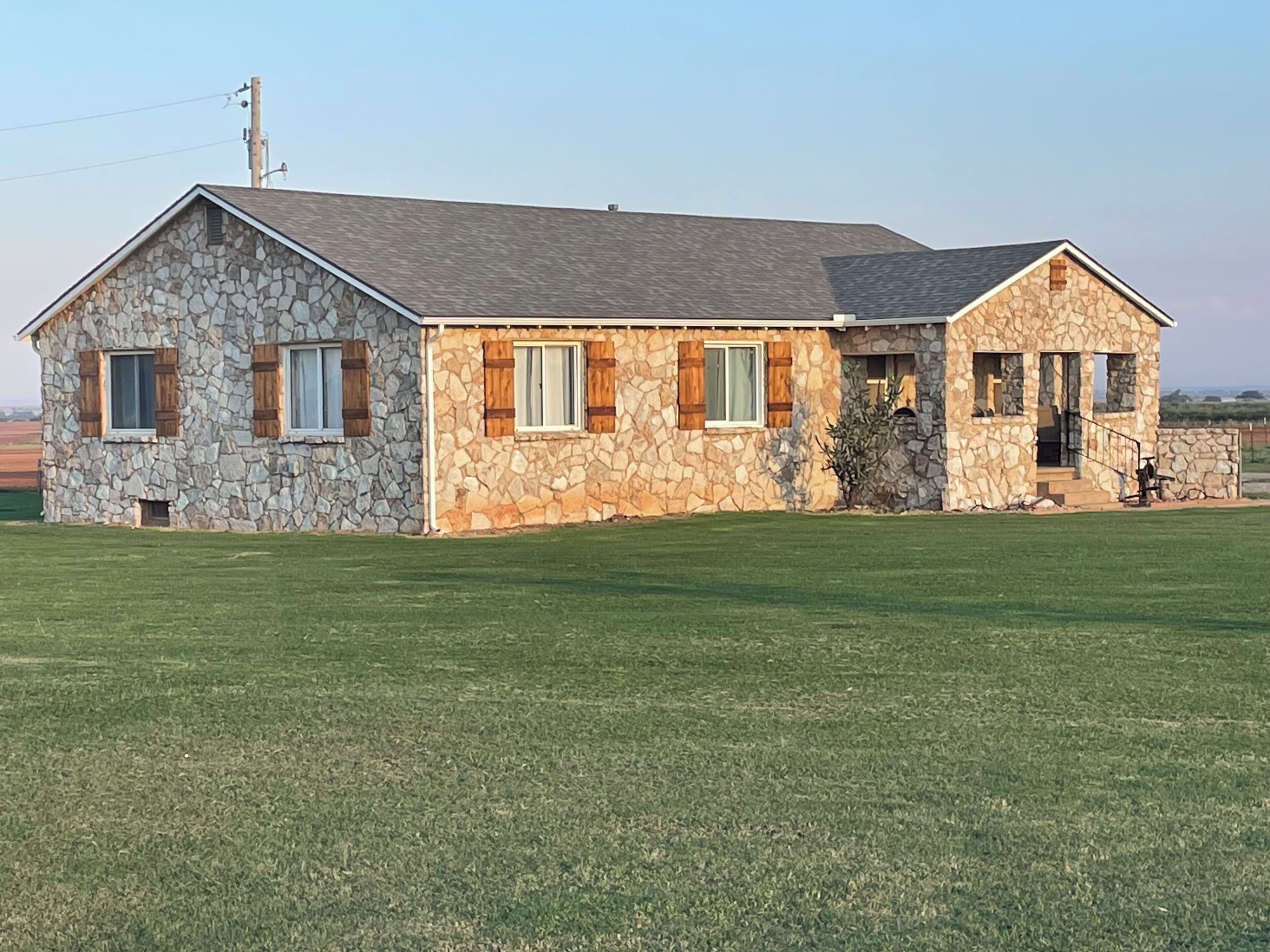 A stone house with a sloped roof, a front porch, and a well-maintained lawn.