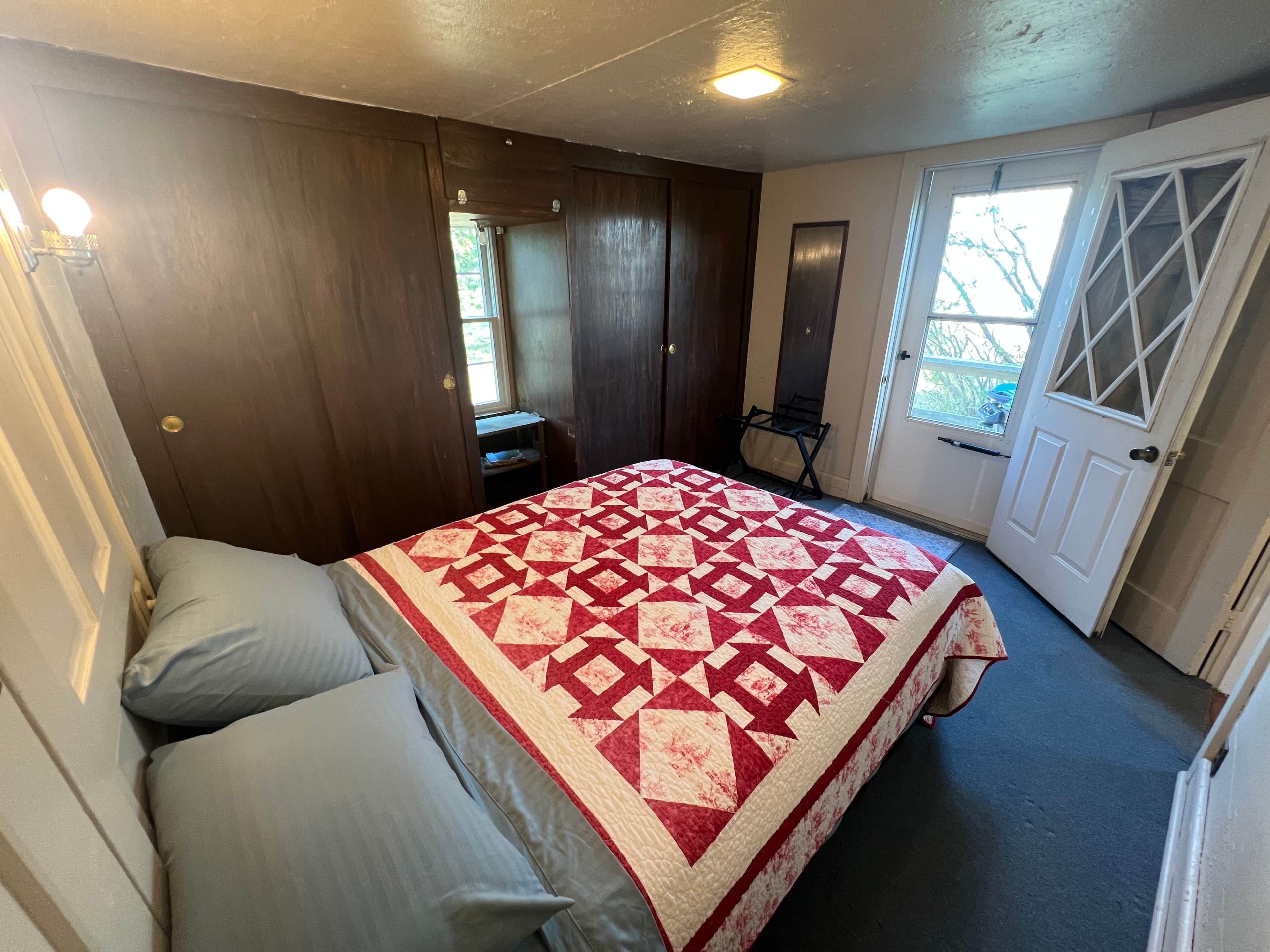 A bedroom with a bed, a dresser, a mirror, and a door leading to a balcony.