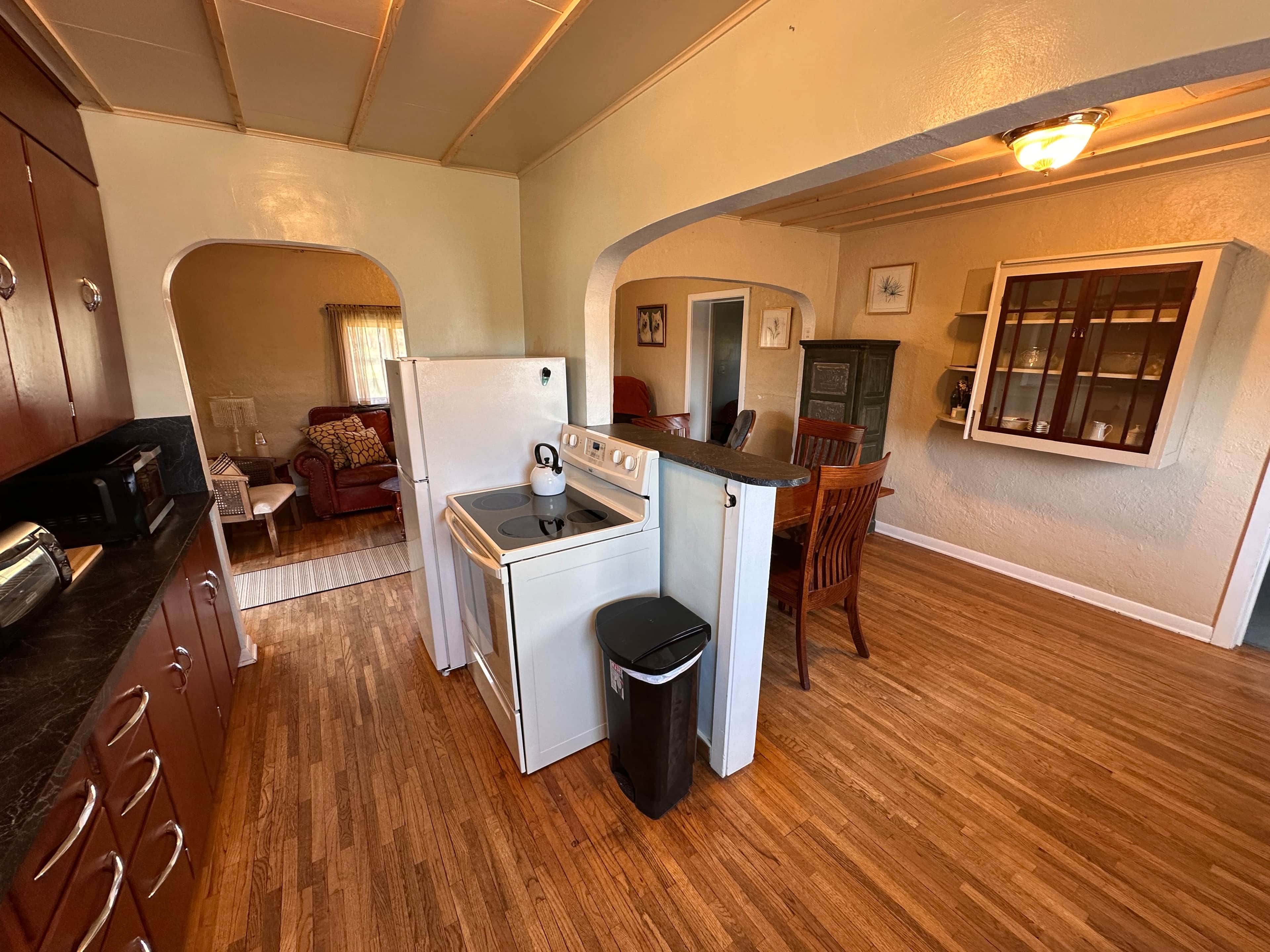 A compact kitchen with a stove, refrigerator, and wooden cabinets.