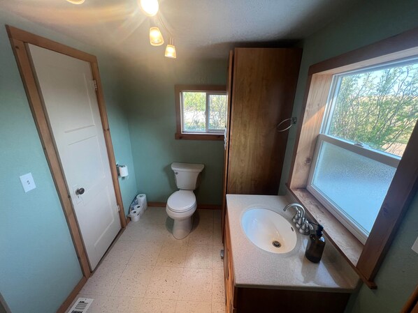 A compact bathroom with a toilet, sink, and window.