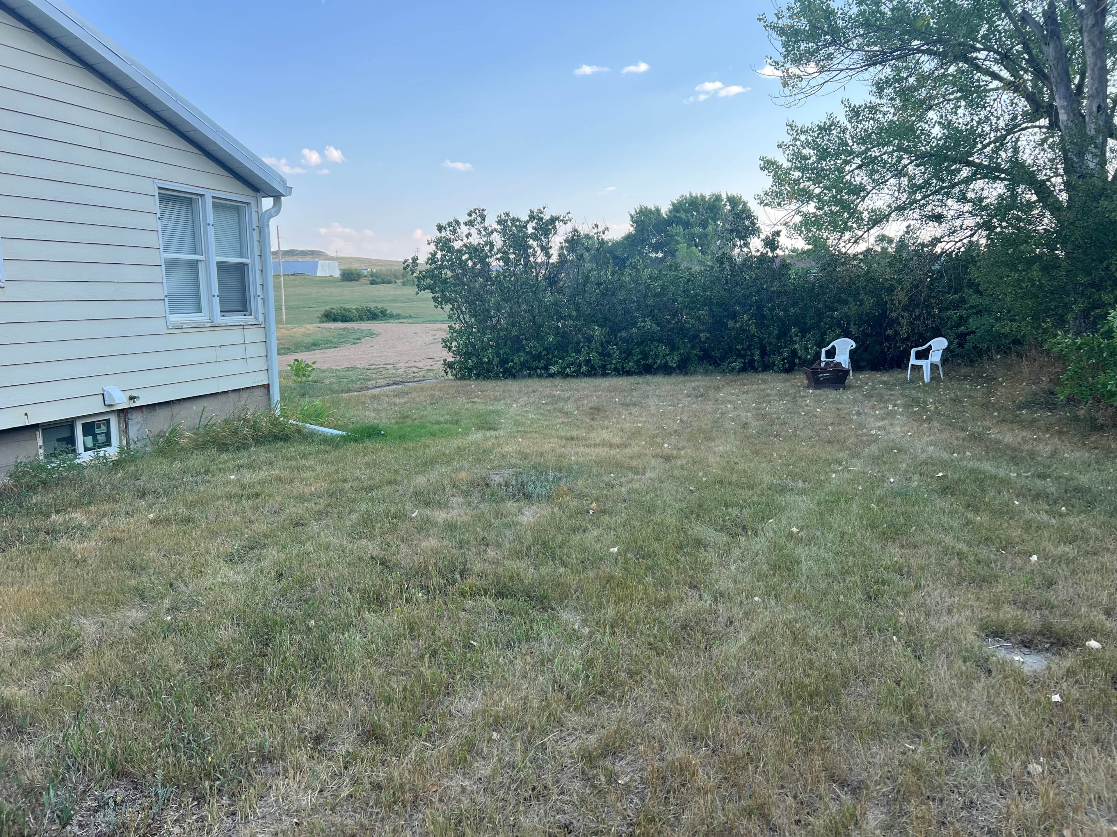 A residential property with a house, a grassy yard, and a path leading to a hill.