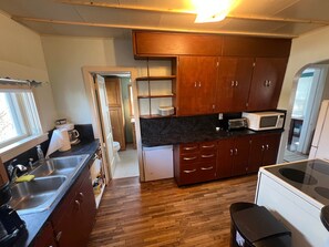 A compact kitchen with wooden cabinets, a microwave, and a sink.