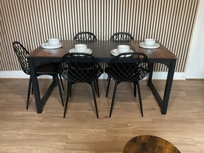 Une table à manger avec quatre chaises, des tasses et des soucoupes blanches.