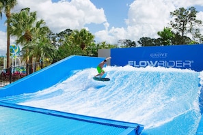 A person surfing on a wave at a water park. - 7BR Themed Home Solara Resort Game Cinema (Kissimmee)