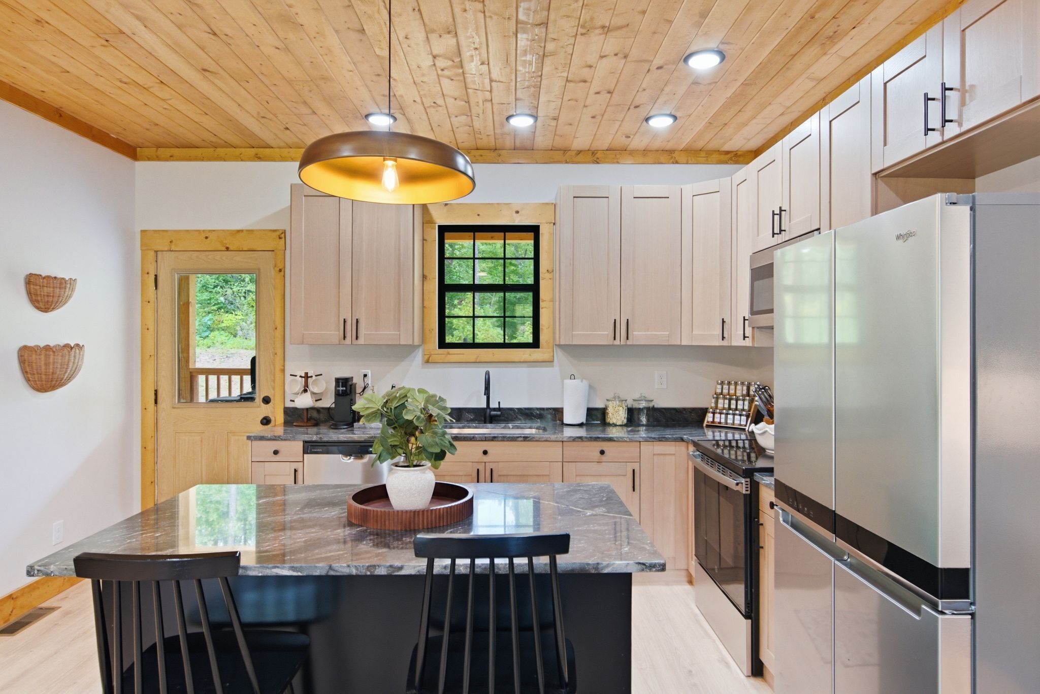 A modern kitchen with wooden cabinets, a central island, and a built-in refrigerator.