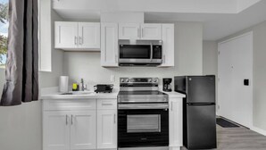 A modern kitchen with white cabinets, a stainless steel microwave, oven, and refrigerator.
