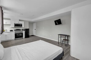Una habitación moderna y minimalista con cama, kitchenette y un pequeño comedor.
