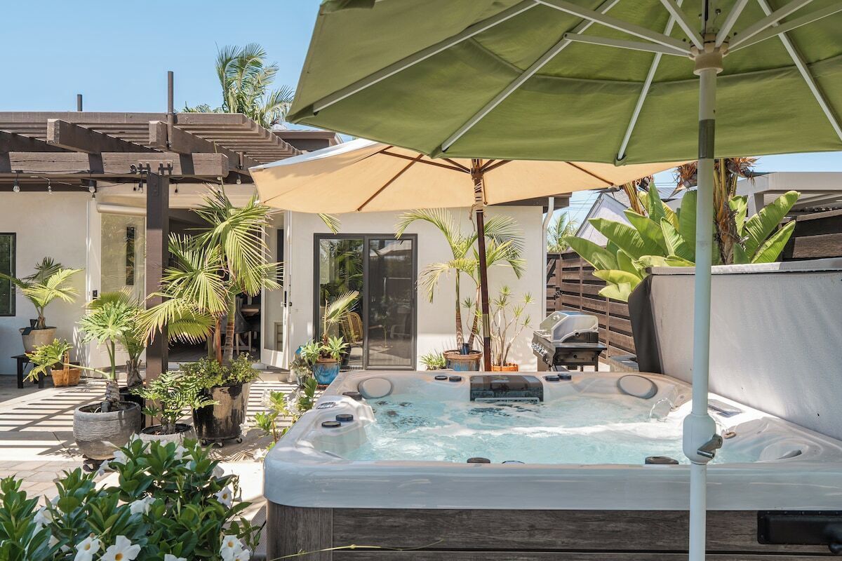 Een hottub omringd door potplanten en een parasol.