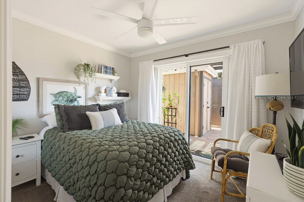 Une chambre à coucher comprenant un lit, une table de chevet, une lampe et une vue sur l’extérieur, accessible par une porte coulissante.