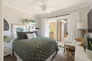 A bedroom with a bed, bedside table, lamp, and a view through a sliding door to an outdoor area. - The Coastal Casa | Spa, Hoops & Garden Oasis (San Diego)