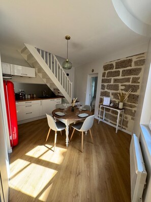 Een eethoek met een houten tafel en stoelen, een trap en een stenen muur.