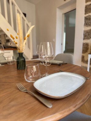 A dining table set with plates, cutlery, and wine glasses, with a vase of dried pampas grass in the center. - ExVoto - Charming Apartment in the Heart of Pézenas (Pézenas)