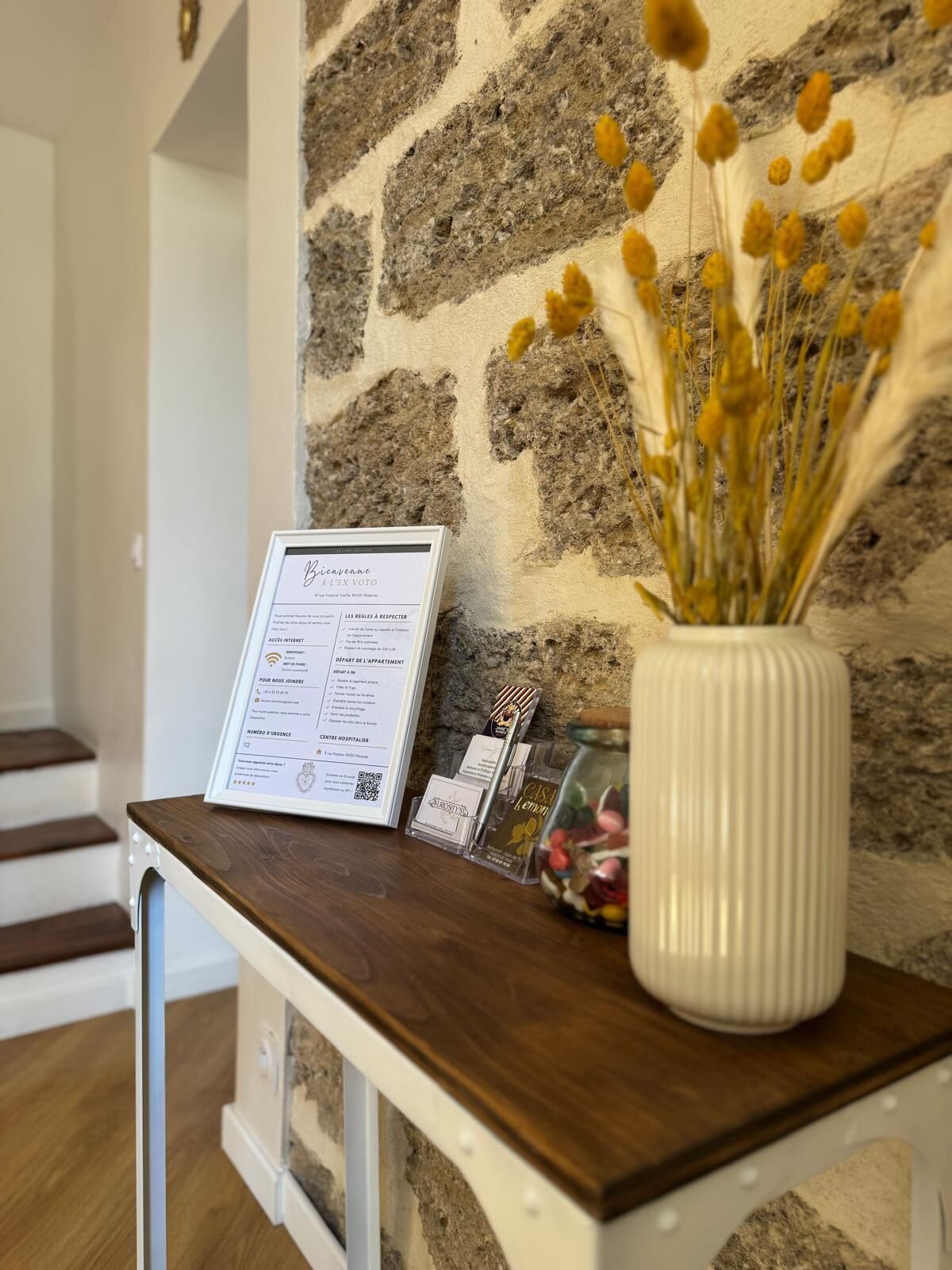 Una recepción con un letrero, un jarrón con flores secas y una pequeña exhibición de objetos.