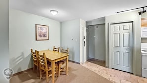 A dining area with a wooden table and chairs, a framed picture on the wall, and a door leading to a kitchen. - Polaris Lodge / Ski-In/Ski-Out / Sleeps 10 (Kimberley)