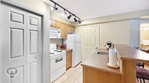 A compact kitchen with white cabinetry, a microwave, a stove, and a refrigerator. - Polaris Lodge / Ski-In/Ski-Out / Sleeps 10 (Kimberley)