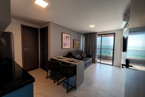 A modern living space with a kitchen, dining area, and a balcony with a view. - Smeralda del Mare by AFT (Ipojuca)