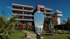 Un hotel moderno con un patio central, un faro y una vista despejada del mar.