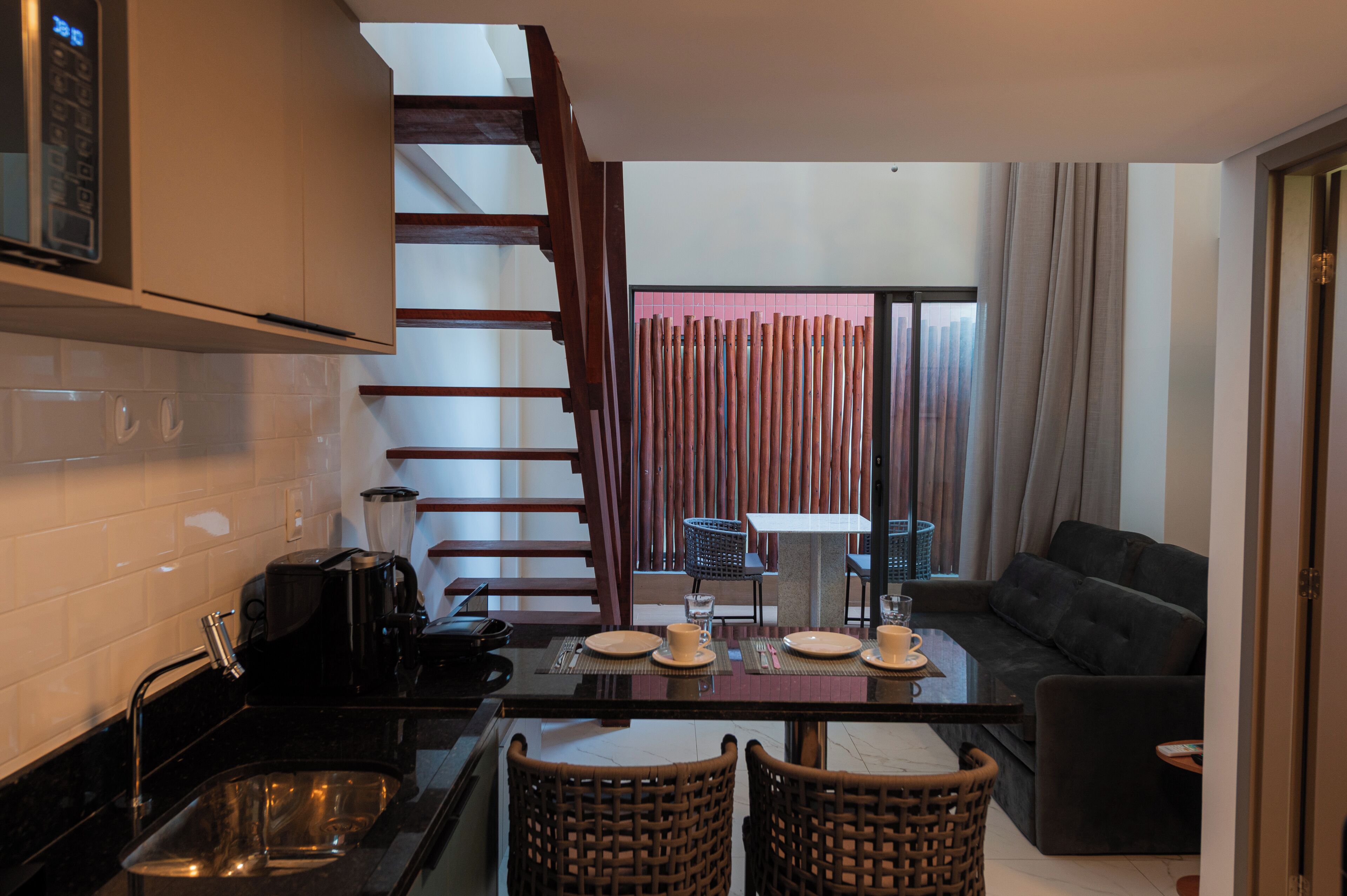Uma cozinha moderna com área de refeições, uma escada e uma sala de estar com sofá.