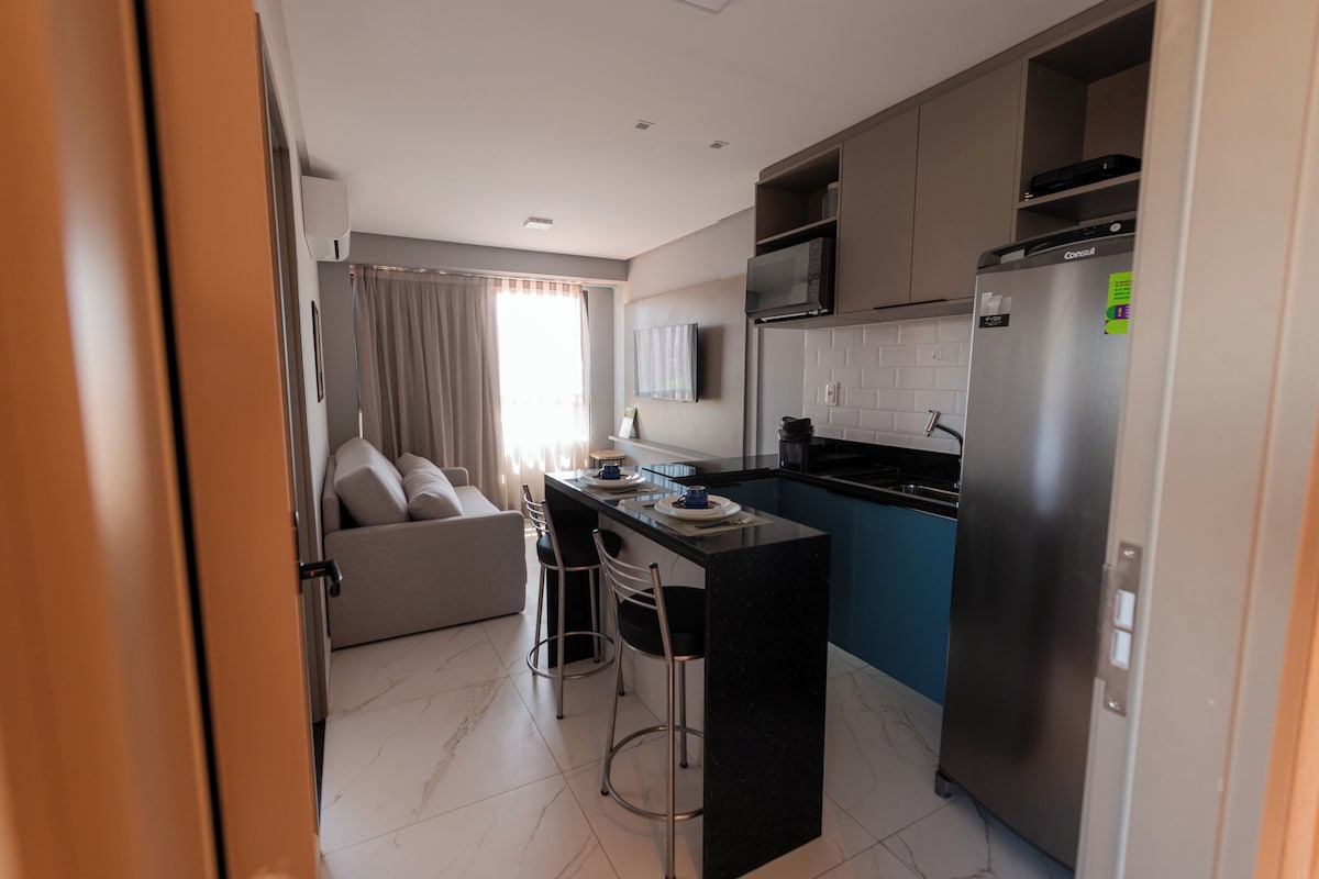 Una cocina moderna con refrigerador integrado, microondas y comedor con taburete de bar.