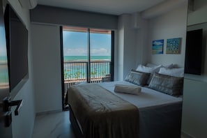 A hotel room with a bed, a TV, a balcony with a view of the sea, and two paintings on the wall. - Smeralda del Mare by AFT (Ipojuca)