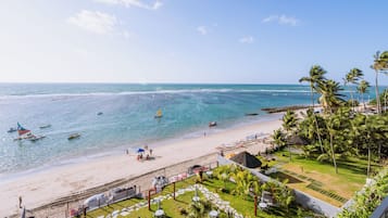 Une plage avec des bateaux, un ciel dégagé et une zone de villégiature dotée d’espaces de détente en plein air.