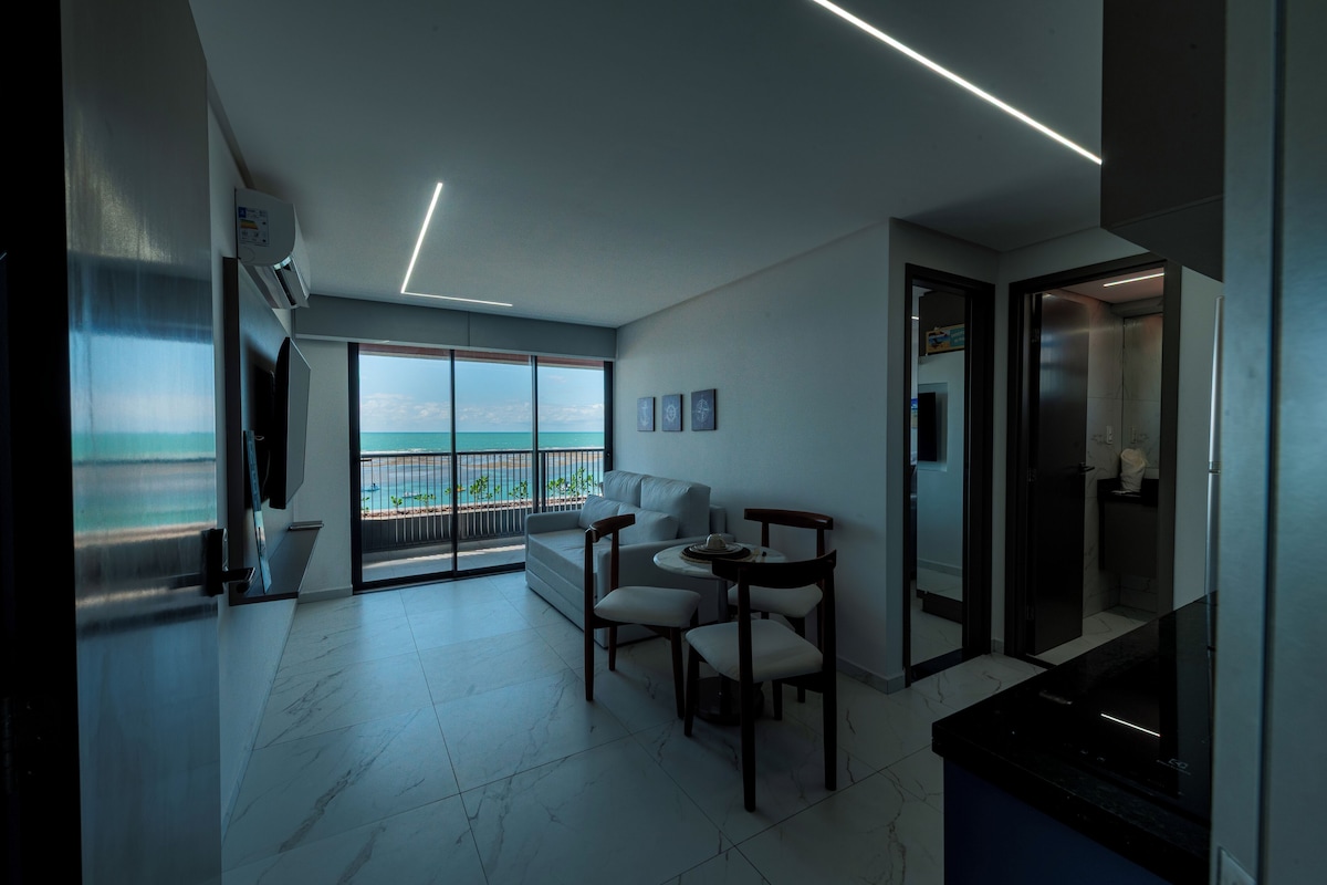 Una sala de estar moderna con vista al mar, un comedor y una cocina.