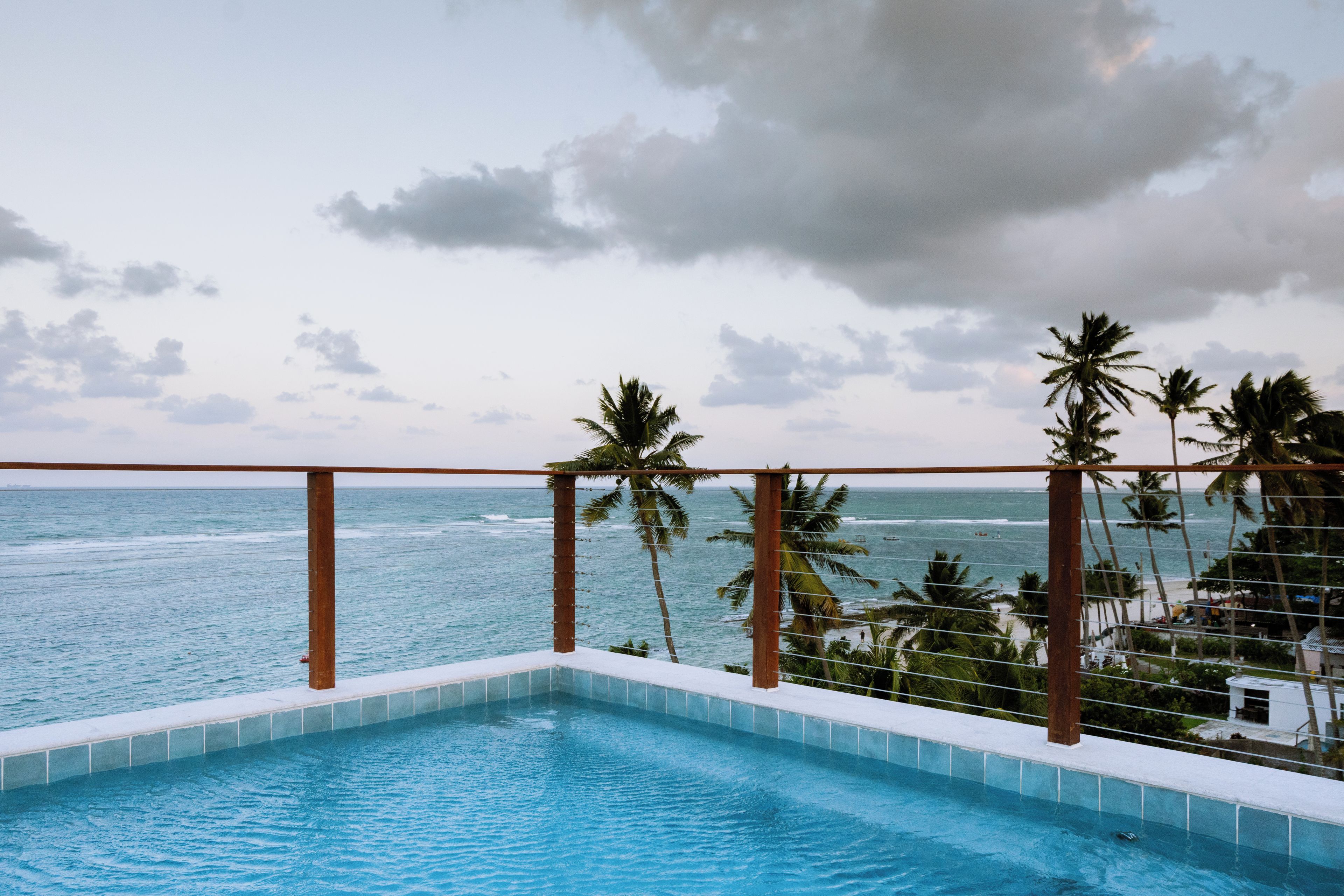 Piscina com vista para o oceano e palmeiras.