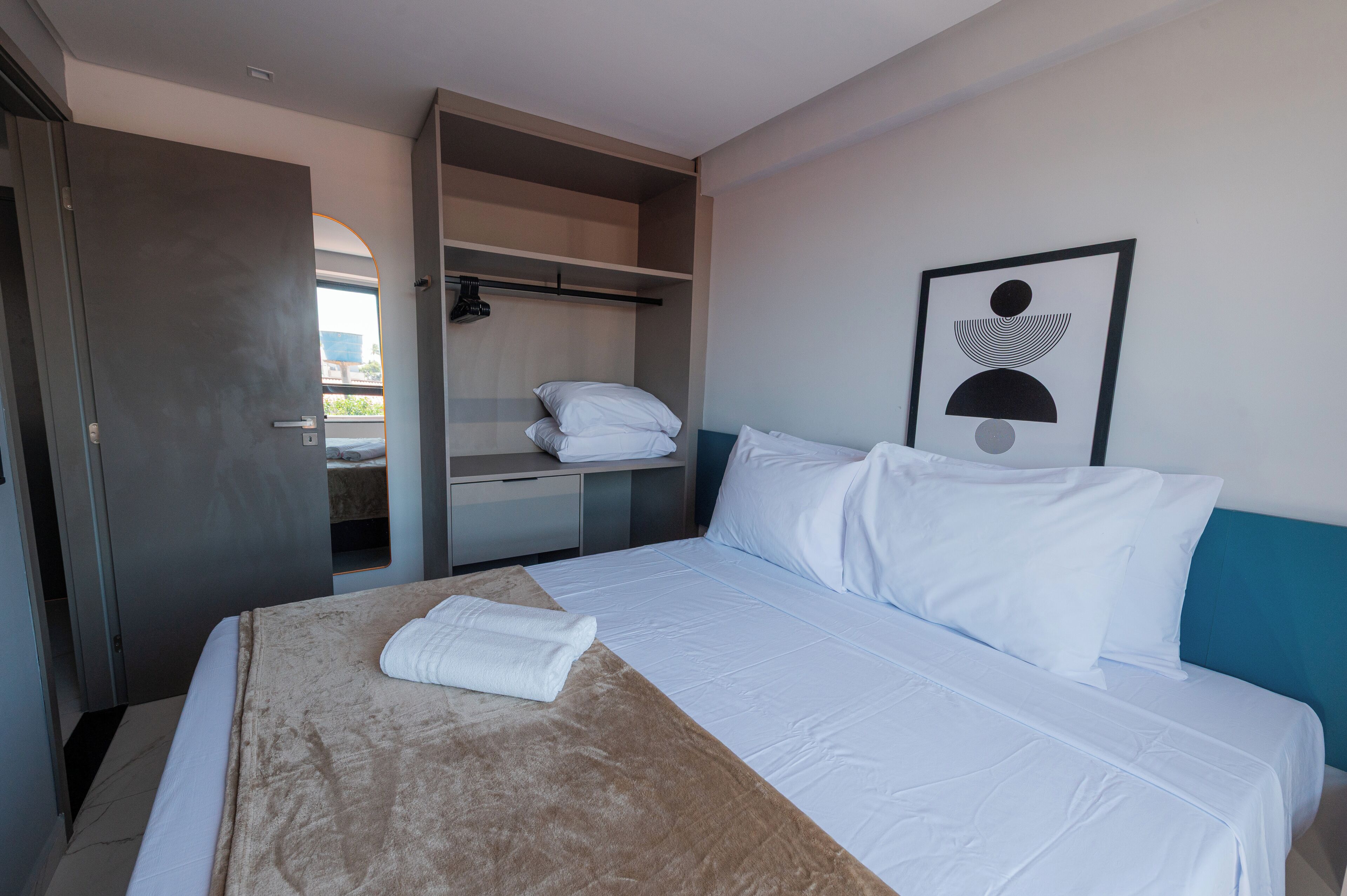 Een hotelkamer met een bed, een garderobe en een inlijsting foto aan de muur.