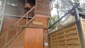 A wooden building with a large door, a small window, and a metal staircase.
