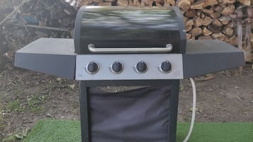 A portable barbecue grill with four control knobs, a built-in thermometer, and a side vent.
