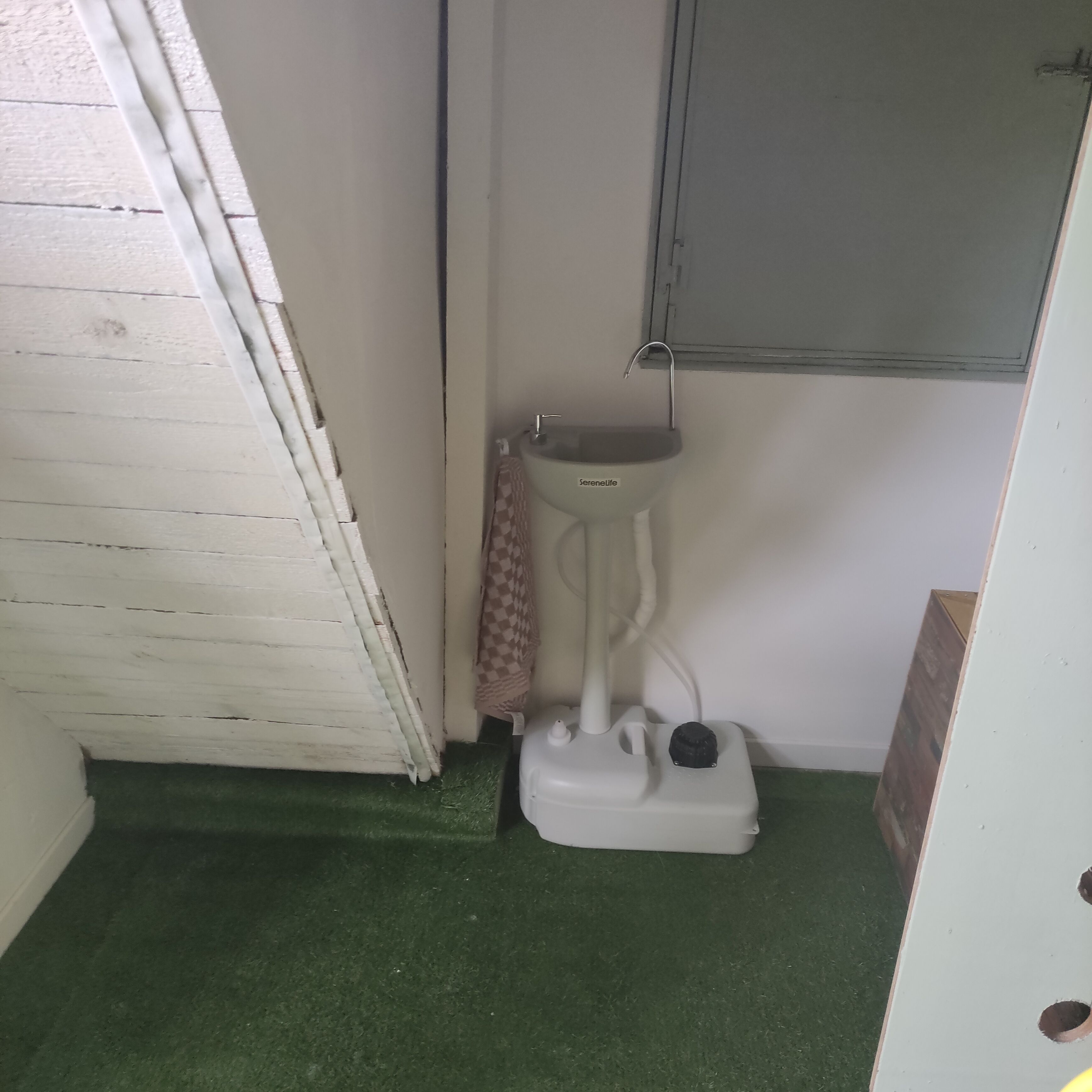 Une petite salle de bain avec des toilettes blanches, un carrelage vert et un meuble au-dessus du lavabo.