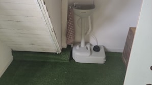 A small bathroom with a white toilet, a green floor, and a cabinet above the sink.